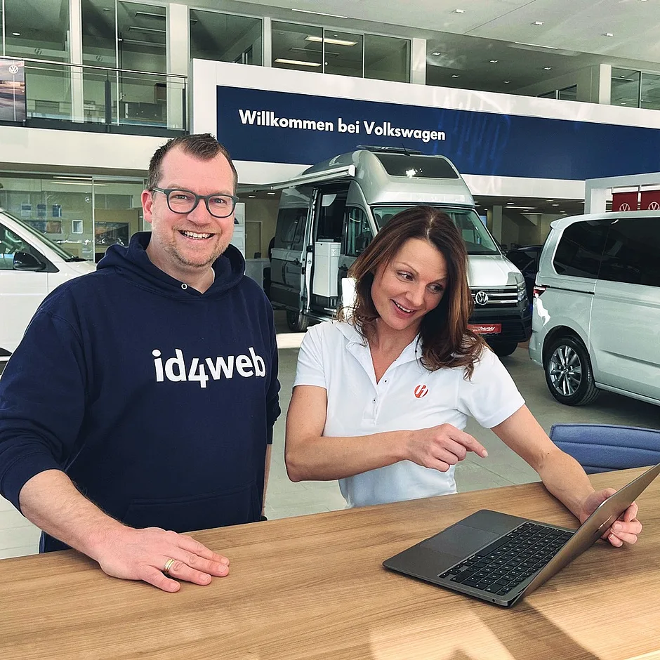 Zwei Personen mit id4web-Kleidung am Laptop in einem Autohaus